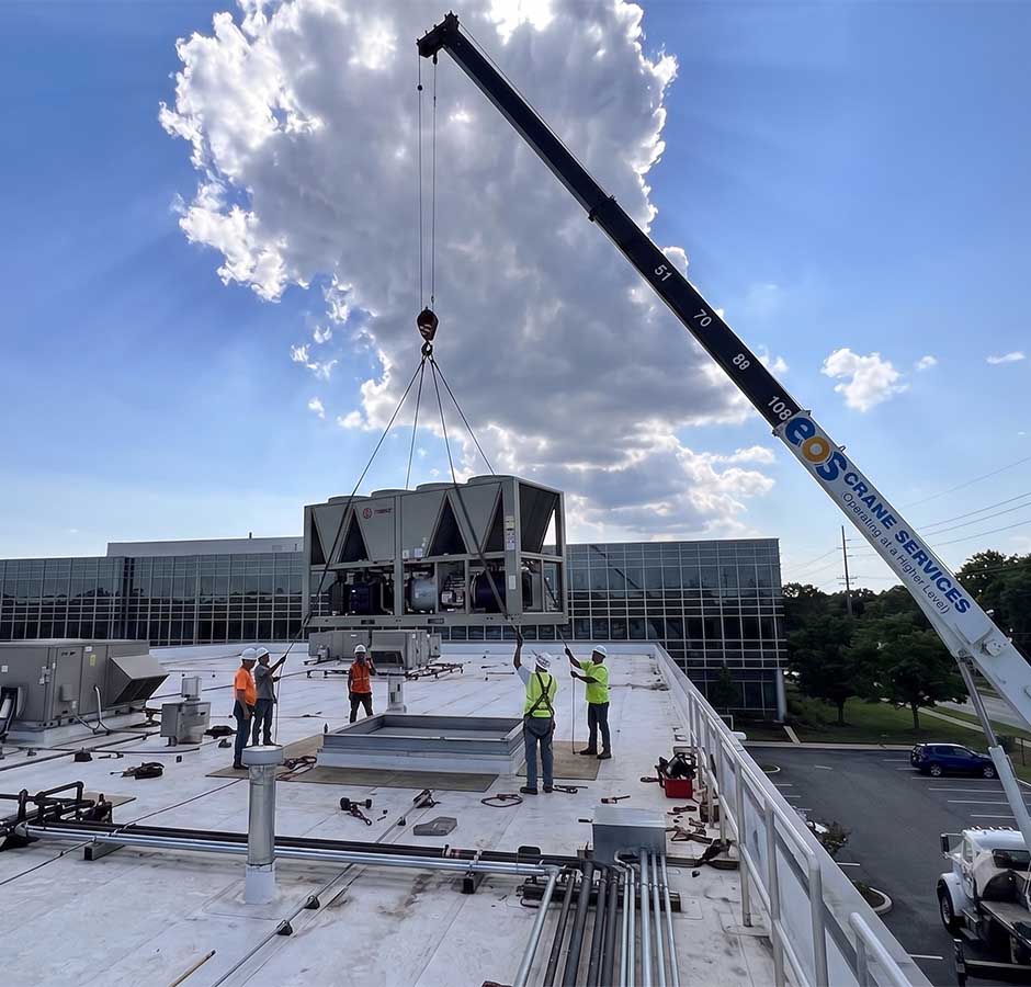 crane lifting heavy equipment up to the roof
